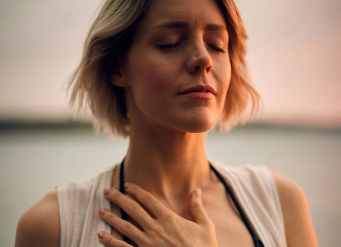 Woman with eyes closed and hand on chest, demonstrating relaxation and the mammalian dive reflex concept.
