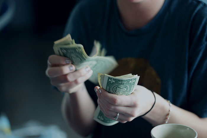 Person counting cash with focus on hands, illustrating subtle red flags that suggest job insecurity risks.