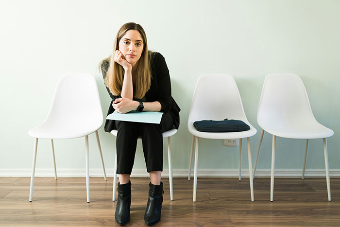 Young woman sitting nervously in an empty waiting room, highlighting subtle red flags of job insecurity.