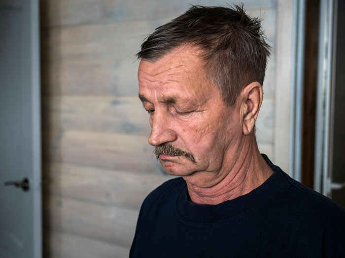 Middle-aged man with a mustache looking down thoughtfully, representing dad demands family skipping Hanukkah gifts.