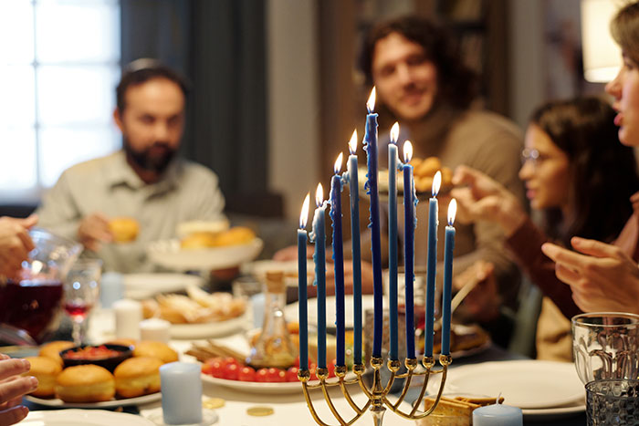 Family celebrating Hanukkah with menorah candles lit, highlighting dad demands no gifts due to son's tantrum.