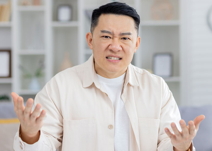 Angry man demanding cousin pay for his cruel prank, expressing frustration in a bright living room setting. Angry man demanding cousin pay for his cruel prank, expressing frustration in a bright living room setting.