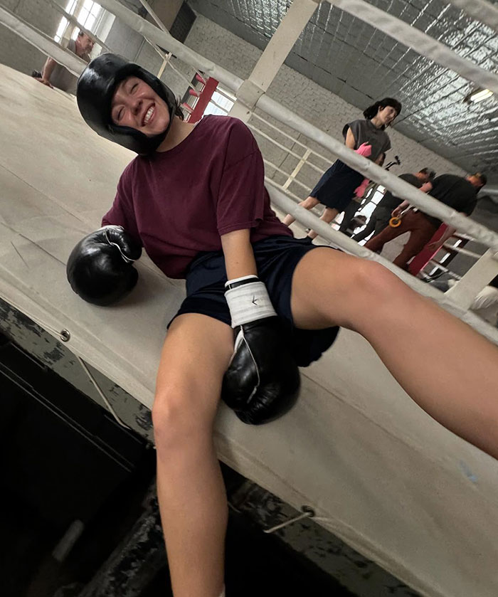 Sydney Sweeney wearing boxing gloves and helmet, smiling and relaxing in a boxing ring during a sports photoshoot. Sydney Sweeney wearing boxing gloves and helmet, smiling and relaxing in a boxing ring during a sports photoshoot.