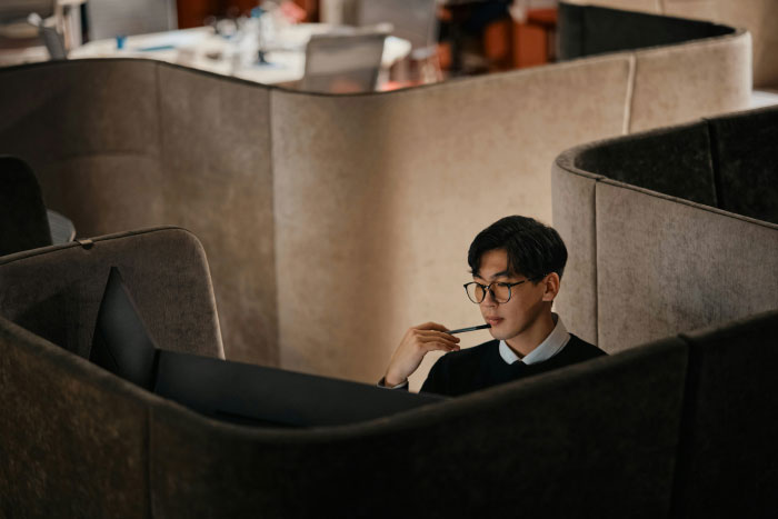 Young professional in glasses working thoughtfully in a private office pod, illustrating AI industry secrets concept.