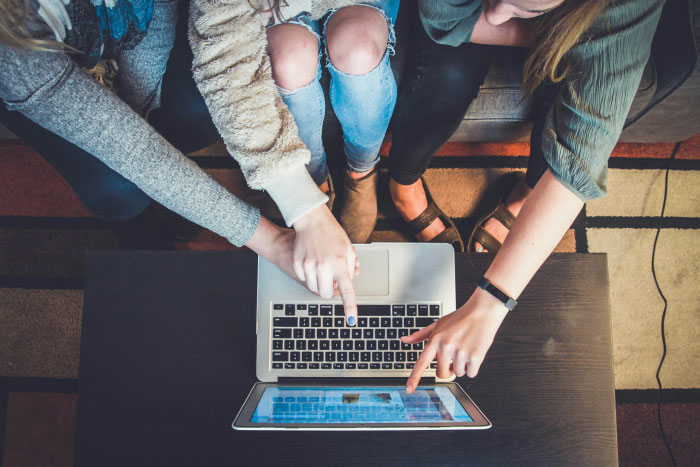 Three people pointing at a laptop screen while sitting, discussing AI industry dirty secrets together.