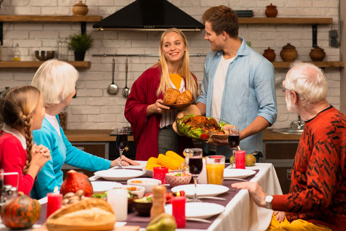 Family and friends gathered at main table for Thanksgiving while son sits annoyed at overflow table. Family and friends gathered at main table for Thanksgiving while son sits annoyed at overflow table.