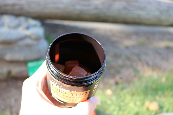 Open container of CBD THC gummies held outdoors, related to mom calling 911 after kids ate her gummies incident. Open container of CBD THC gummies held outdoors, related to mom calling 911 after kids ate her gummies incident.