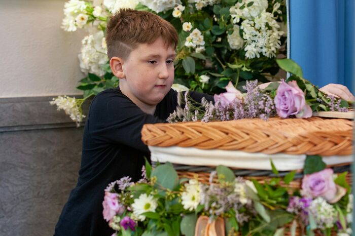 Young boy placing flowers on a decorated coffin during a funeral, highlighting moments when funerals did not go as expected.