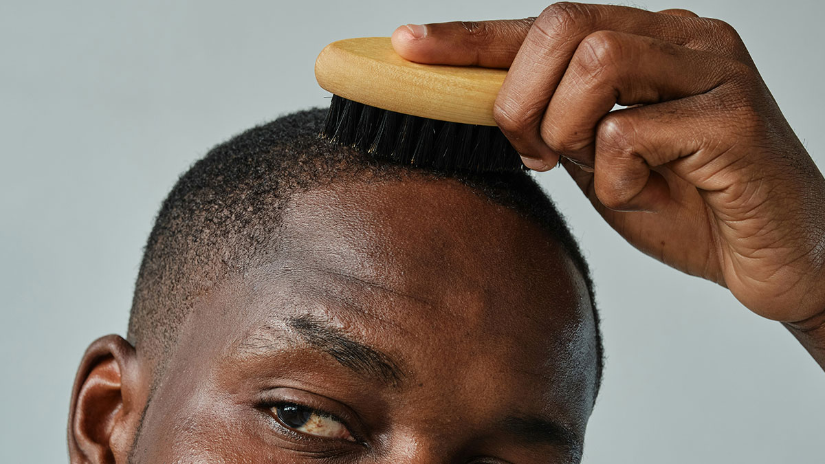 Man grooming his hair with a brush, representing confidence and themes related to female roasts hitting men.