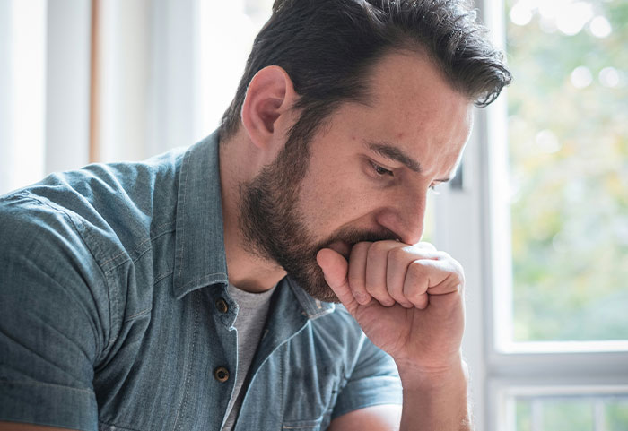 Man in a blue shirt looking thoughtful and reflective, possibly affected by female roasts hitting him hard.