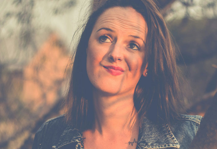 Woman making a sarcastic expression outdoors in denim jacket, embodying female roasts that hit men hard and memorable.