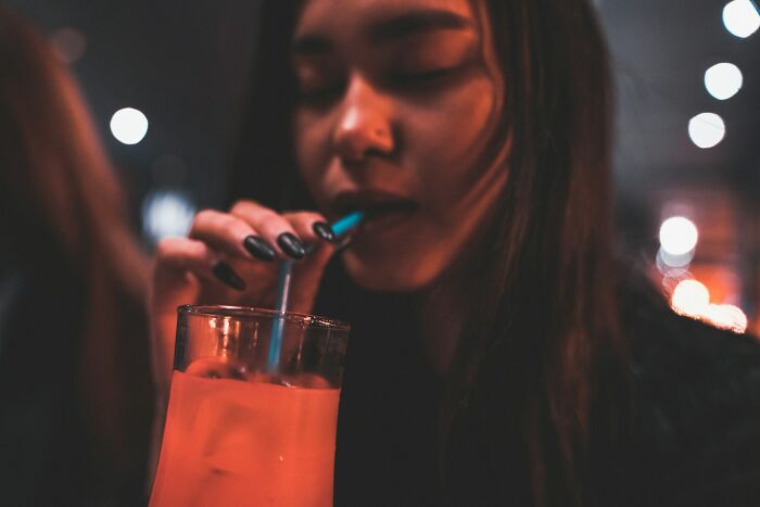 Young woman with long hair sipping a drink through a straw, illustrating everyday things people accidentally did wrong.