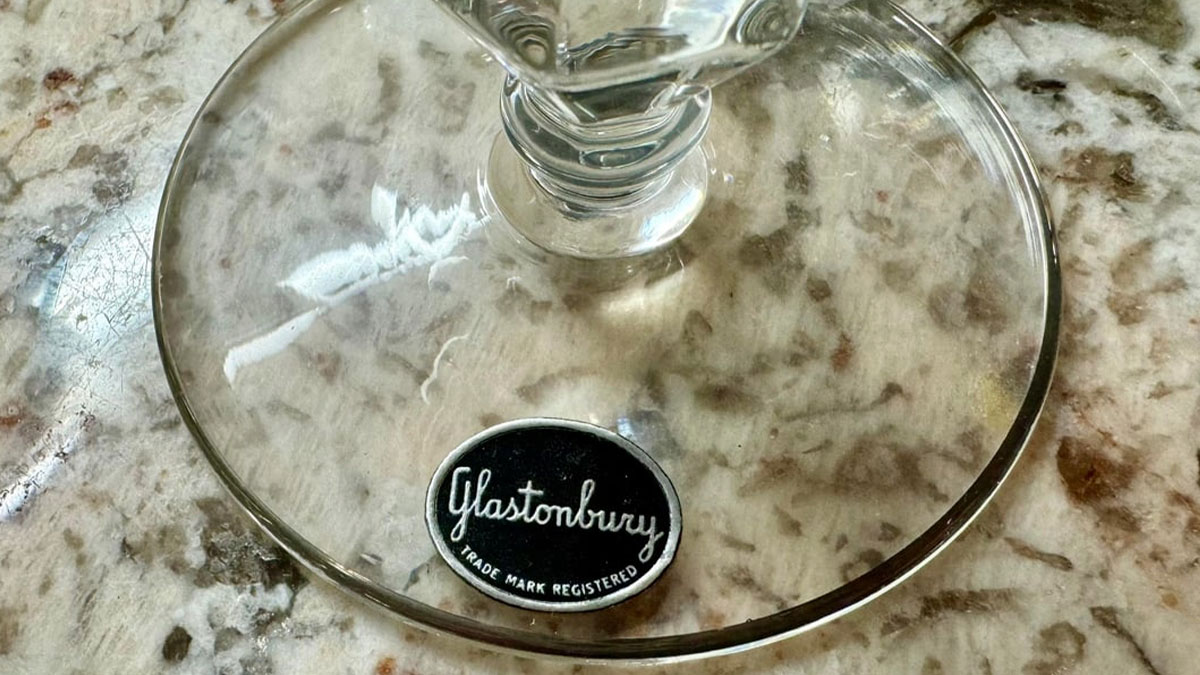 Close-up of a glass base with a Glastonbury label on a textured surface, illustrating small design mistakes.