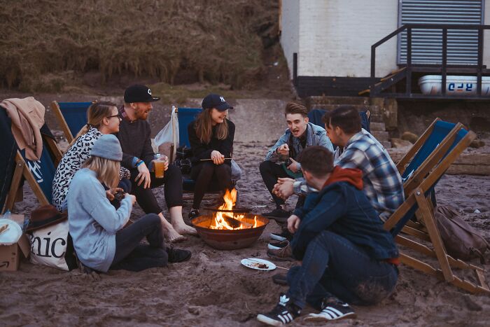 Group of friends sitting around a beach bonfire, illustrating secrecy in a relationship with a guy who has a girlfriend. Group of friends sitting around a beach bonfire, illustrating secrecy in a relationship with a guy who has a girlfriend.