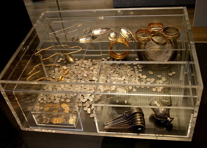 Ancient gold and silver coins and jewelry displayed in a clear case illustrating interesting today I learned facts.