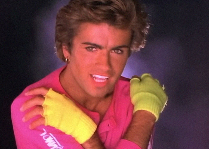 Man wearing bright pink shirt and yellow gloves posing with crossed arms in vibrant retro style photo, interesting today I learned facts