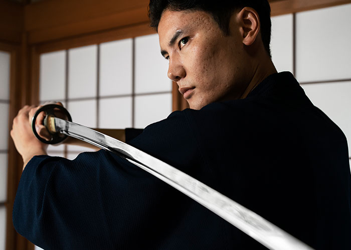 Young man practicing martial arts, holding a katana sword in a traditional Japanese room for interesting facts article.