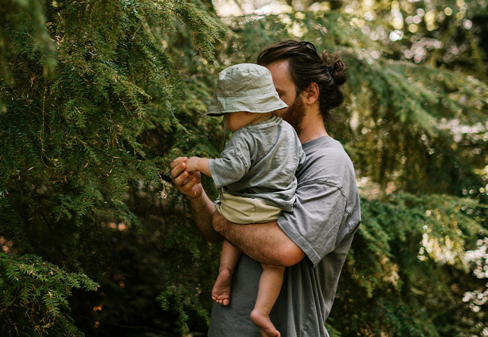 Father holding toddler in nature, illustrating dad privileges and experiences shared by moms in parenting discussions.