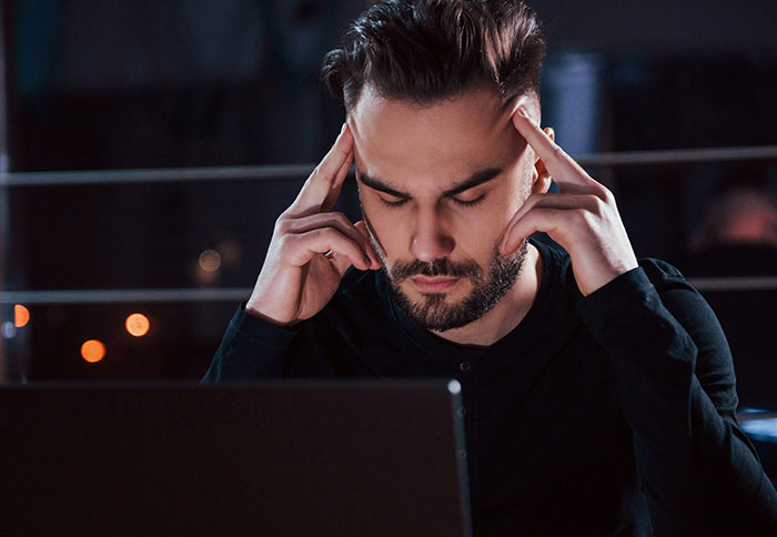 Man concentrating intensely while working on a laptop, reflecting on dad privileges and parental challenges at night.