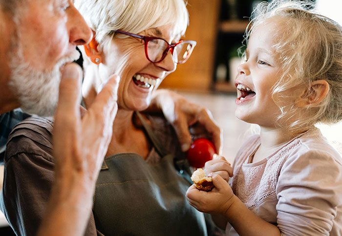 Older couple and young girl laughing together, highlighting dad privileges and family moments shared with moms.
