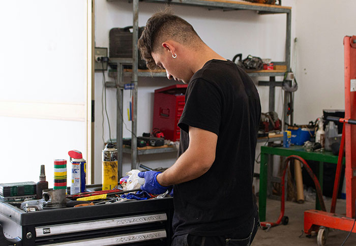 Man working in a garage surrounded by tools, illustrating dad privileges and the challenges moms discuss.