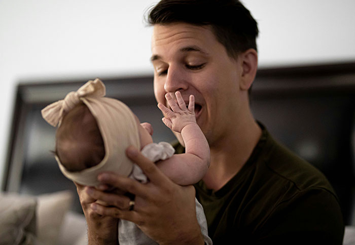 Man holding baby girl wearing headband, highlighting dad privileges in parenting moments that can feel unfair to moms.