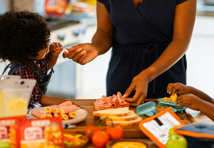 Mom preparing lunch for kids in kitchen illustrating dad privileges that feel unfair to mothers and parents.