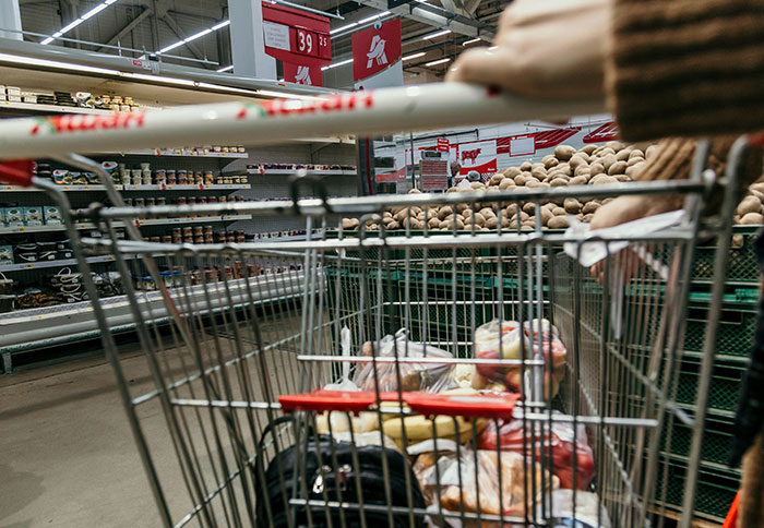 Shopping cart filled with groceries in a supermarket aisle, reflecting everyday mom experiences and dad privileges discussions.