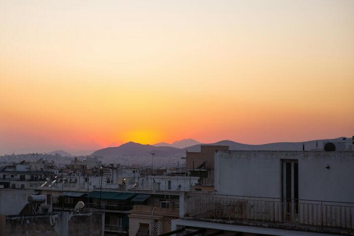 Sunset over a Greek village with rooftops and mountains in the background, capturing village life atmosphere. Sunset over a Greek village with rooftops and mountains in the background, capturing village life atmosphere.