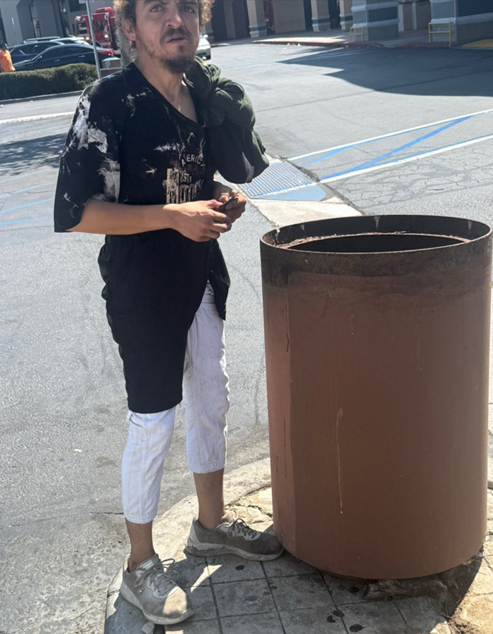 Former child actor Tylor Chase standing outdoors in casual clothes near a large rust-colored trash can on a sunny day. Former child actor Tylor Chase standing outdoors in casual clothes near a large rust-colored trash can on a sunny day.