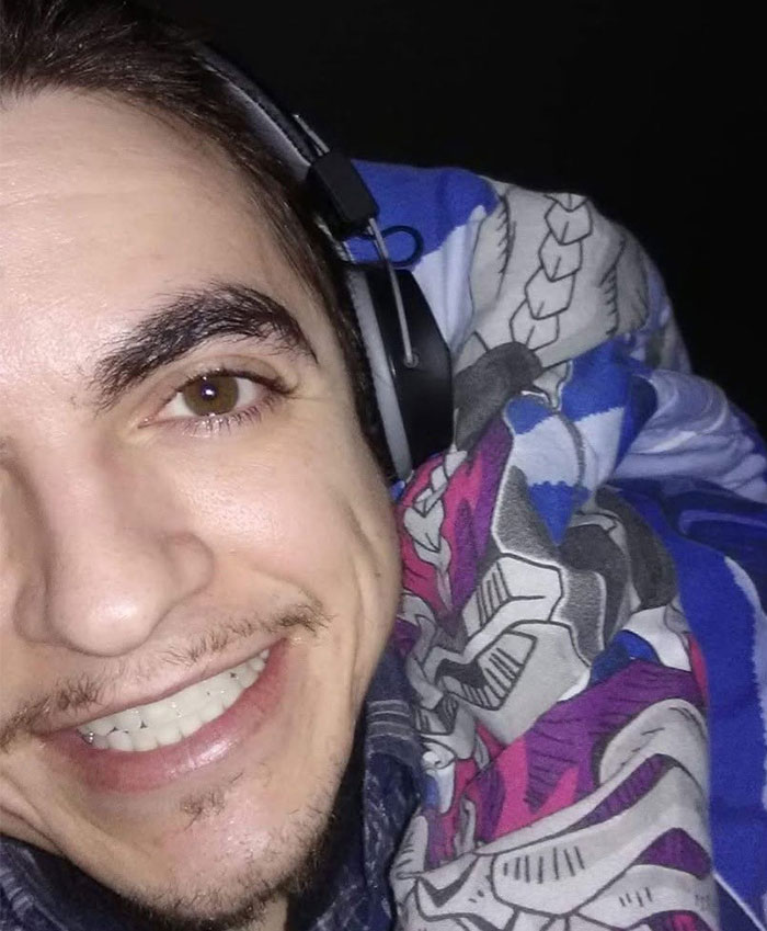 Close-up of Tylor Chase smiling warmly while wearing headphones and wrapped in a colorful blanket, related to hospitalization news. Close-up of Tylor Chase smiling warmly while wearing headphones and wrapped in a colorful blanket, related to hospitalization news.