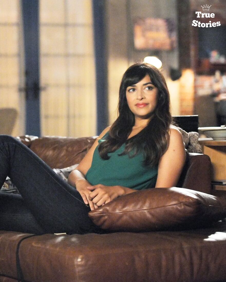 Young American personality relaxing on a brown leather couch in a casual setting with soft indoor lighting.