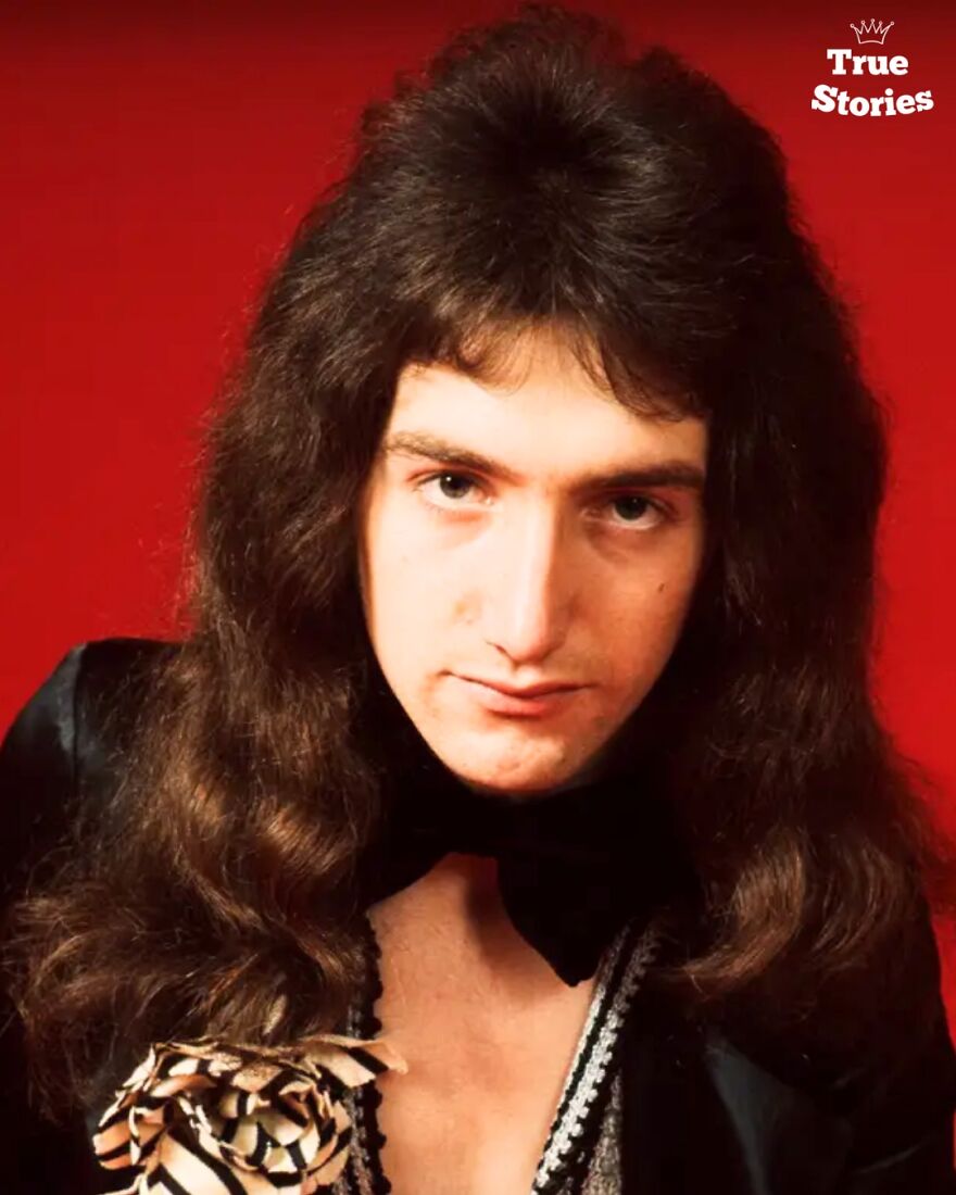 Young American personality with long dark hair and a flower accessory, against a red background in a portrait style.