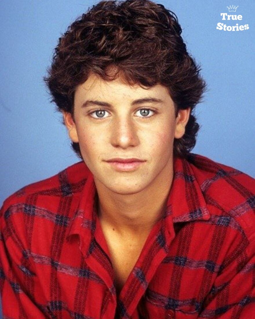 Young American personality wearing a red plaid shirt, posing against a blue background for a portrait photo.