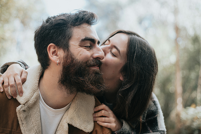 Couple outdoors with woman kissing man on cheek, illustrating SAHM feeling poor despite monthly fun money from husband. Couple outdoors with woman kissing man on cheek, illustrating SAHM feeling poor despite monthly fun money from husband.