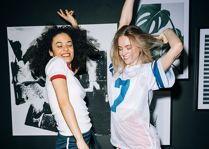 Two women dancing happily indoors, capturing a moment of strange things neighbors accidentally saw together.
