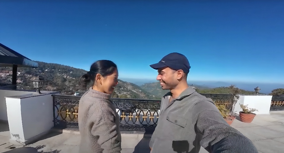 A couple enjoying scenic views of hidden gems in Himachal Pradesh with clear blue skies and mountain landscape.