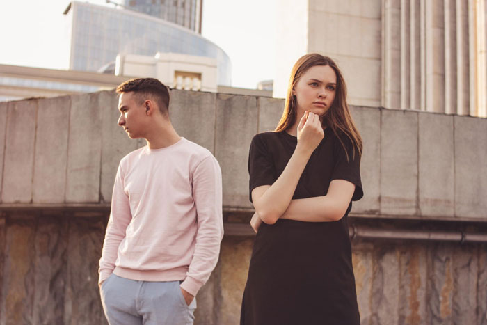 Young couple standing apart looking upset, illustrating tension in a boyfriend girlfriend spending and Hawaii trip conflict. Young couple standing apart looking upset, illustrating tension in a boyfriend girlfriend spending and Hawaii trip conflict.