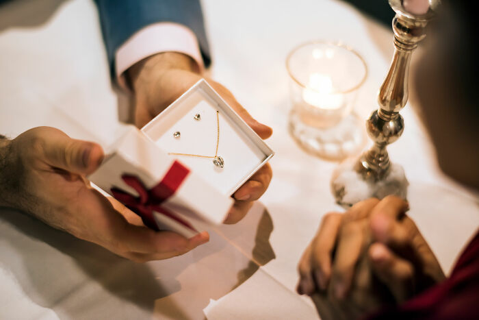 Person presenting a holiday gift necklace to their partner, highlighting relationship insights from expert warnings. Person presenting a holiday gift necklace to their partner, highlighting relationship insights from expert warnings.