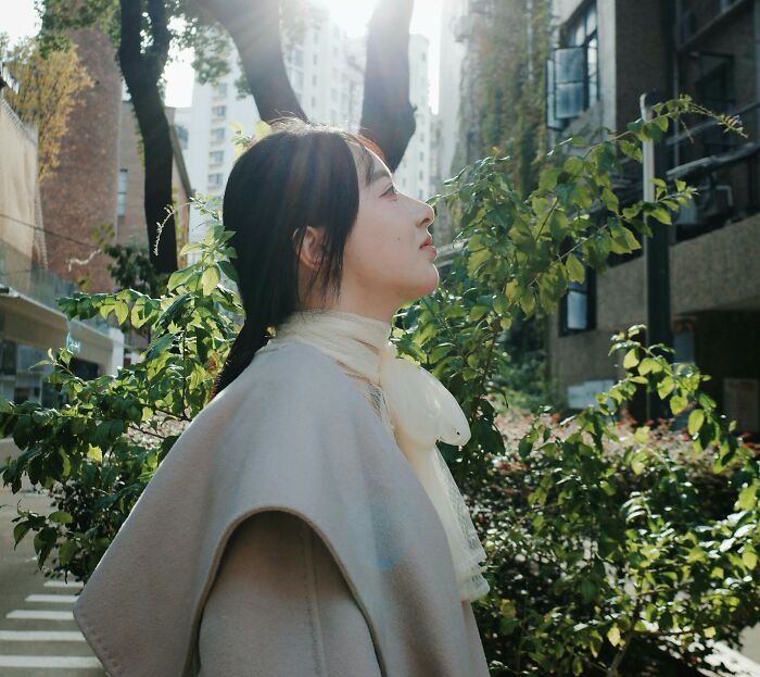 Young woman outdoors in sunlight looking contemplative, reflecting on dark secrets and changed perceptions.