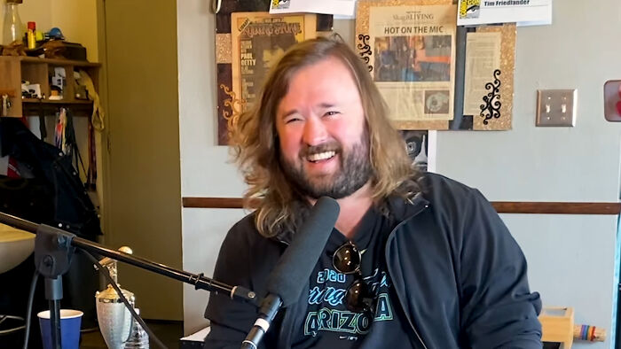 Man with long hair and beard speaking into a microphone in a casual setting about celebrities people think suffer.