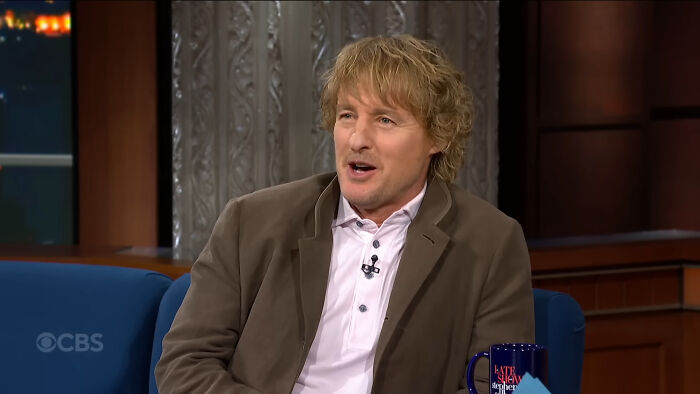 Actor with tousled hair wearing a brown jacket and white shirt on a talk show discussing celebrities people think suffer.
