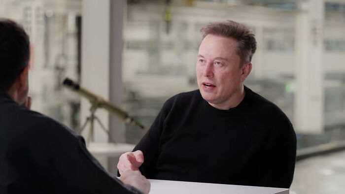 Elon Musk in a black shirt during an interview, representing celebrities people think suffer in public.