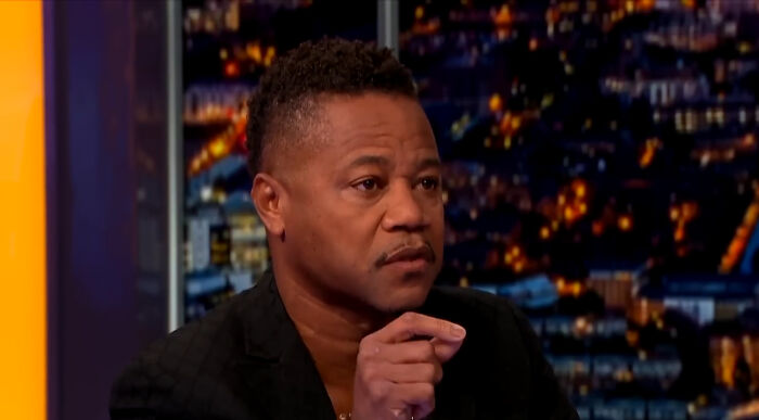 Actor in a black jacket sharing fascinating secrets about celebrities during a nighttime interview on television.