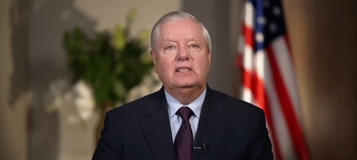 A man in a suit speaking in front of an American flag, representing people think celebrities closet skeletons.