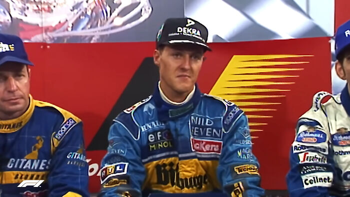 Race car drivers in branded blue racing suits sitting during a press event, highlighting celebrities people think suffer.