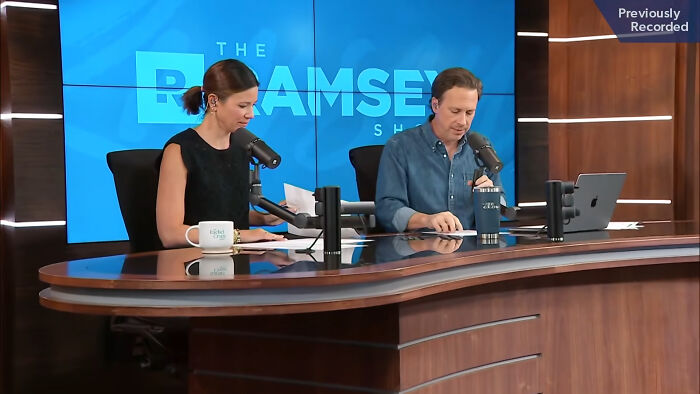 Two podcast hosts discussing dark secrets on a professional set with microphones and laptops visible.