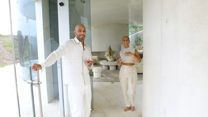 Two people smiling and holding drinks while standing in a modern home, highlighting people think celebrities closet skeletons.