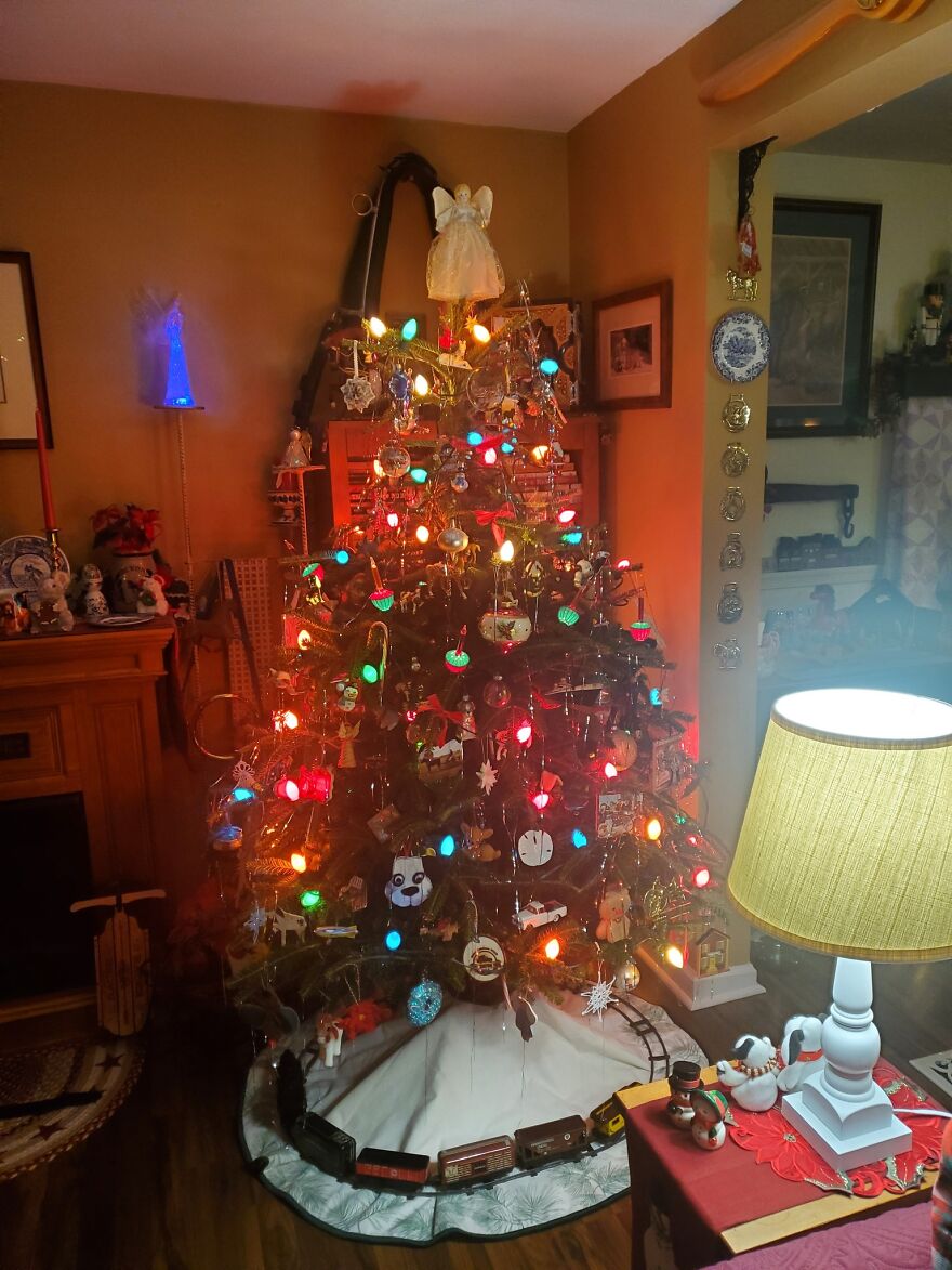 Vintage Christmas tree decorated with colorful nostalgic lights and ornaments in a cozy living room setting