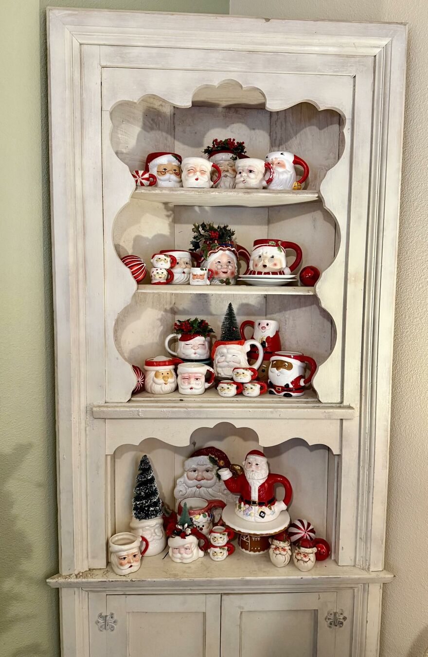 Vintage Christmas decorations displayed on white wooden shelves featuring Santa-themed mugs, mini trees, and ornaments.